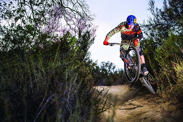 A man biking on a dirt path through a grass field.